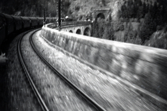 Bergstraße mit Eisenbahnstrecke und Viadukt in Schneelandschaft